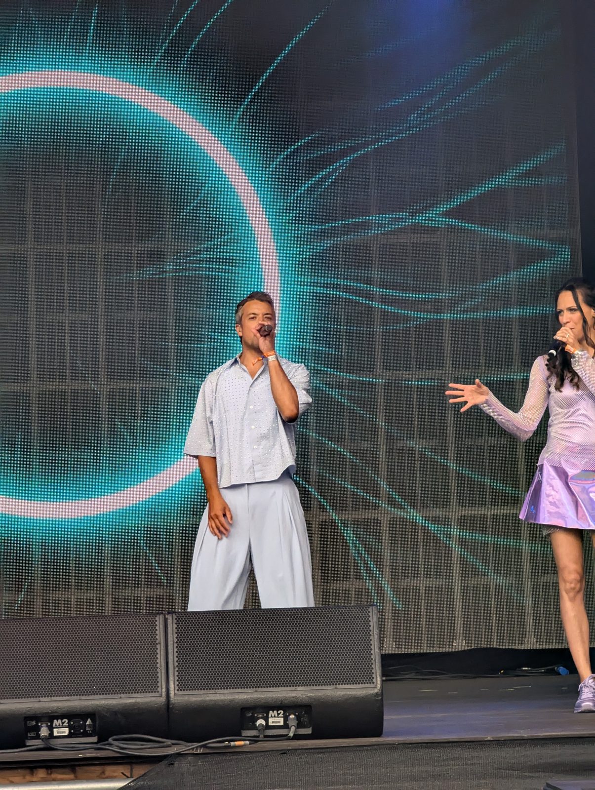 Two A*Teens members singing together on stage at Mighty Hoopla in London, 2025