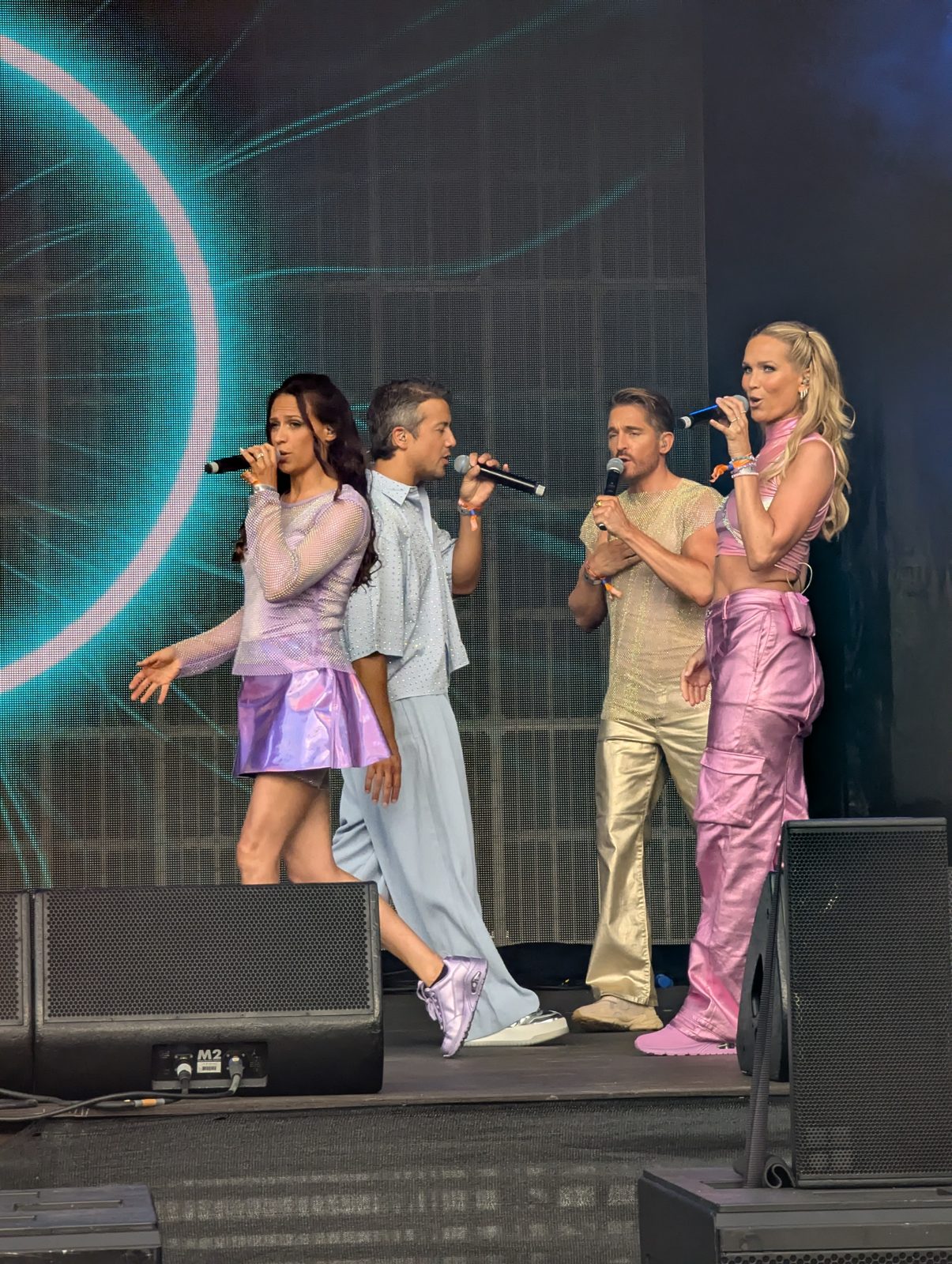 All four A*Teens members performing together on stage at Mighty Hoopla in London, 2025