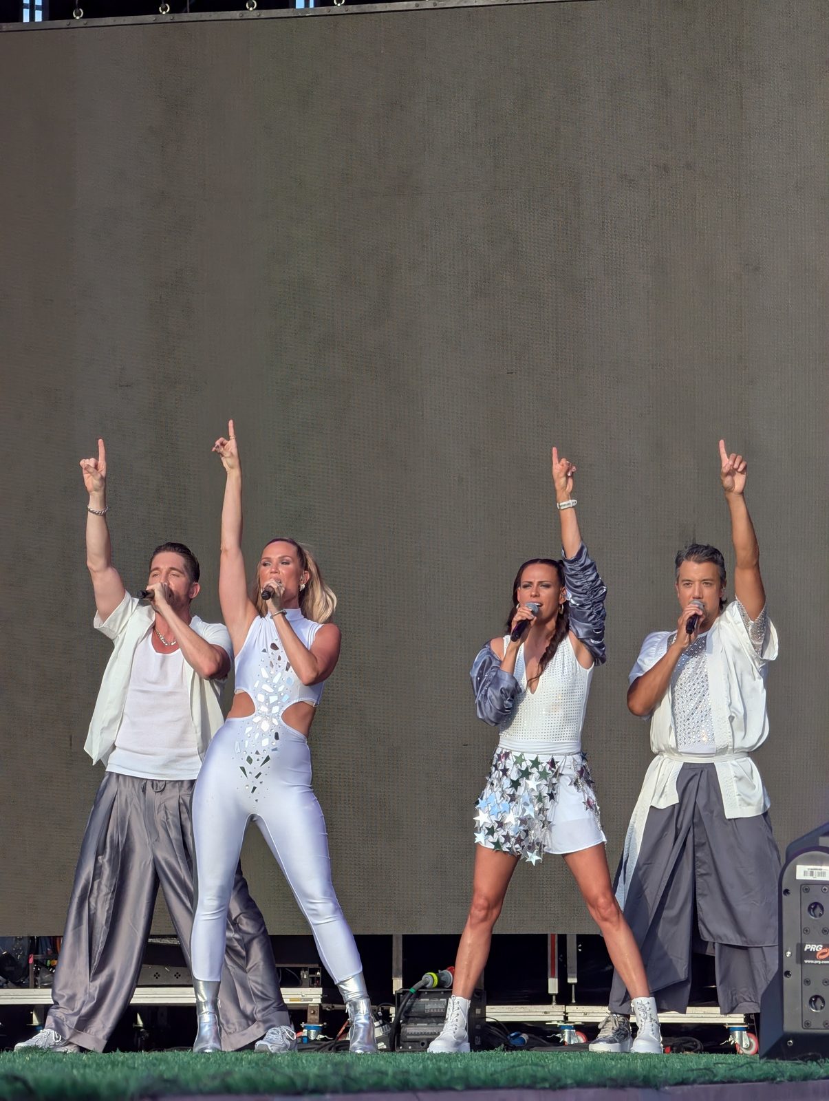 All four A*Teens members pointing to the sky on stage in Madrid, 2025