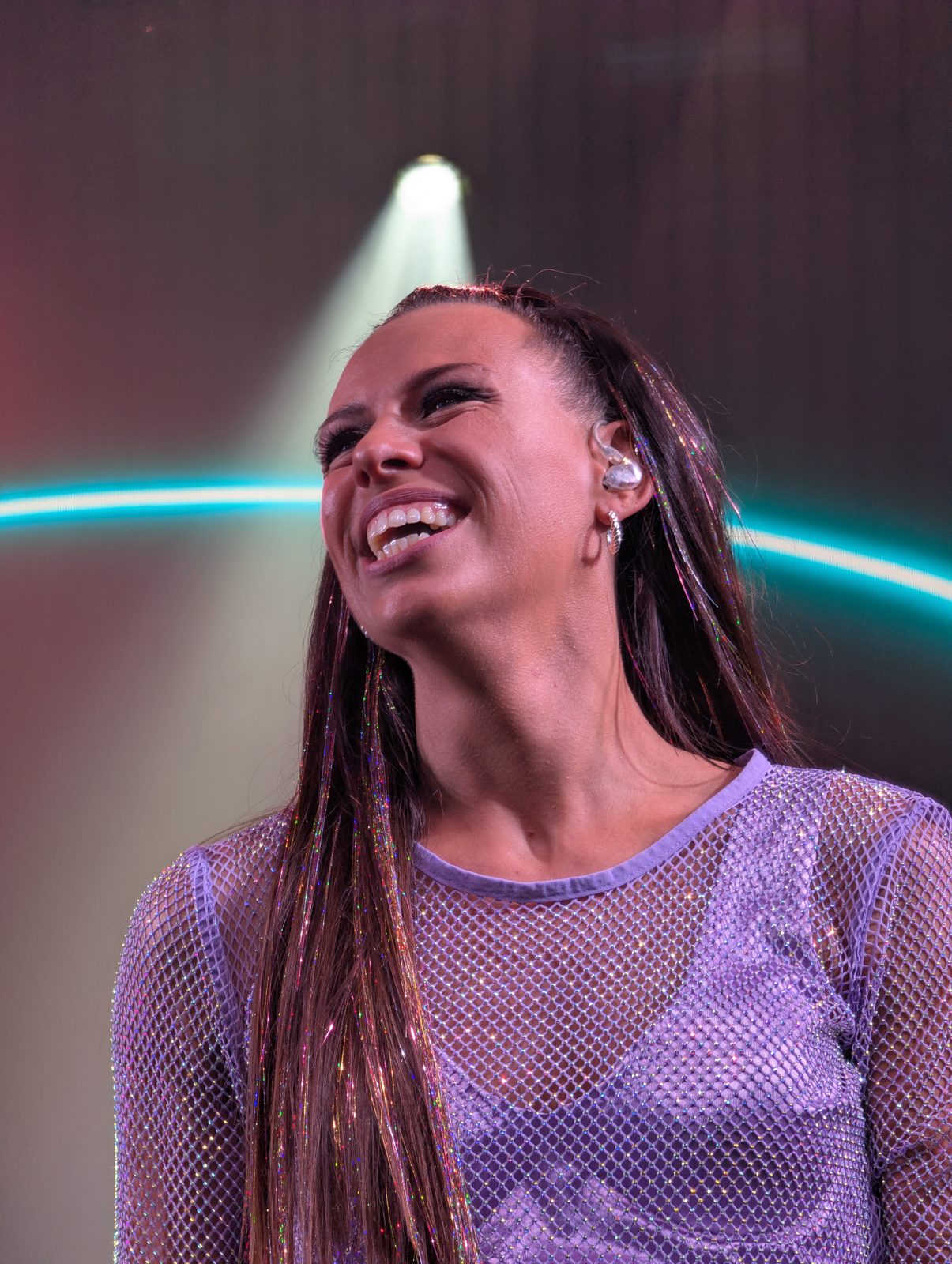 A*Teens member laughing on stage under teal stage lighting in Mexico City, 2025