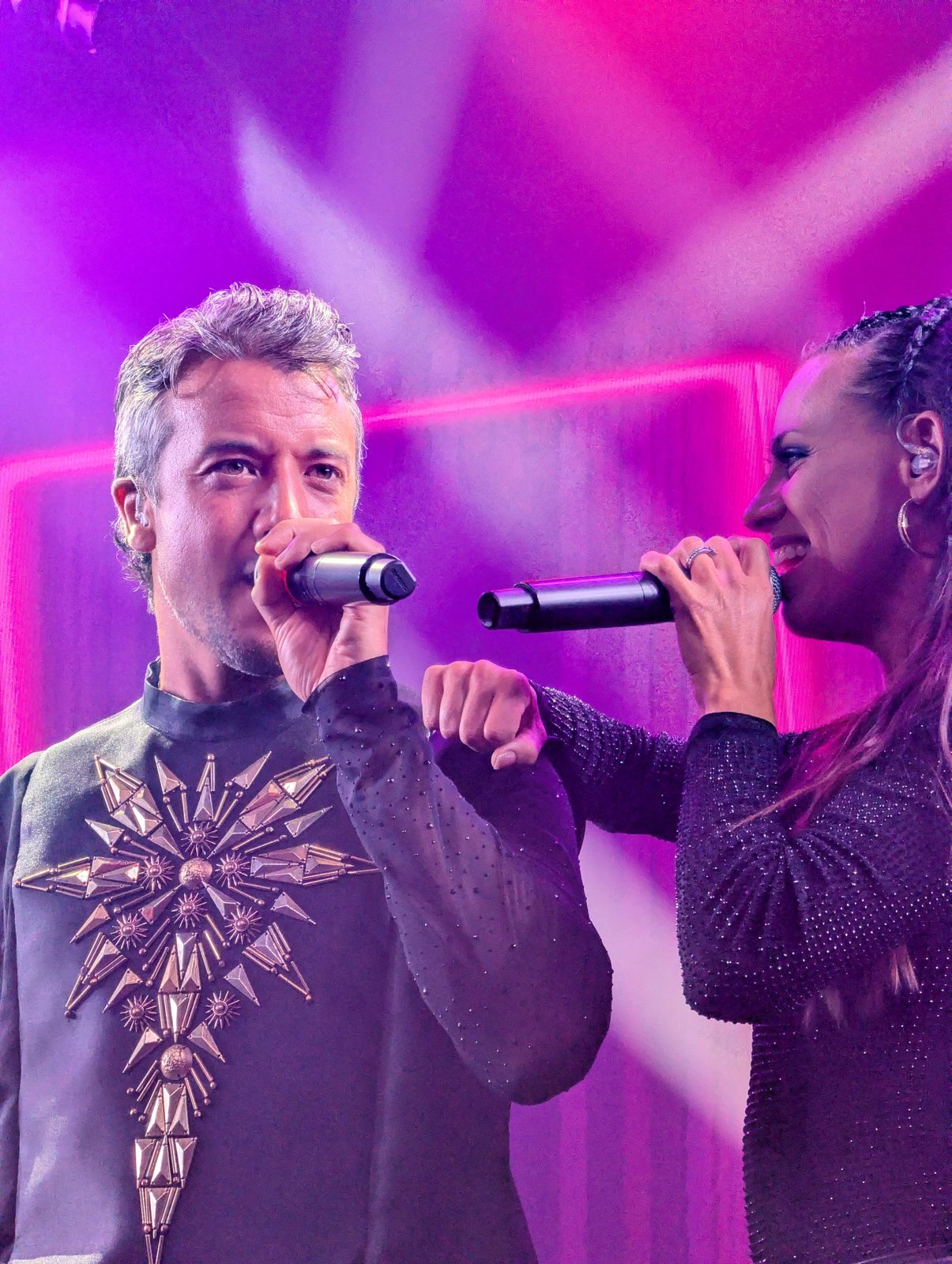 Two A*Teens members singing together on stage in Mexico City, 2025