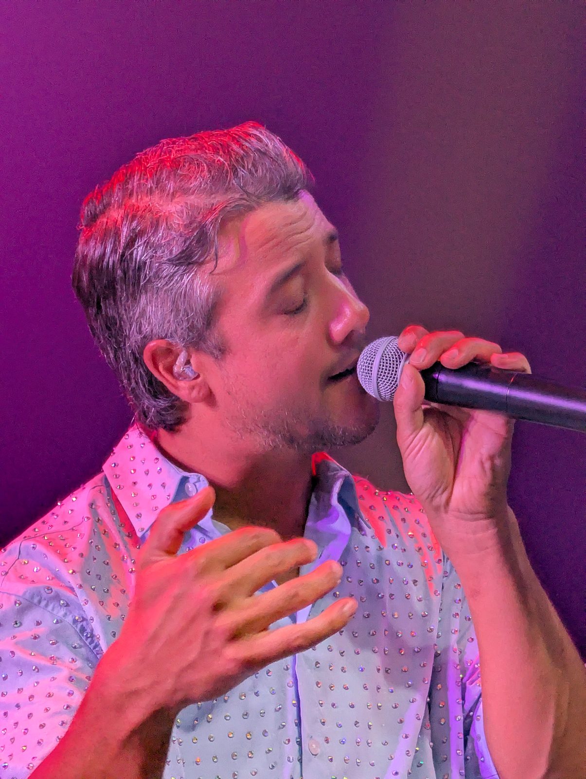 A*Teens member singing in close-up under pink and purple stage lighting in Mexico City, 2025